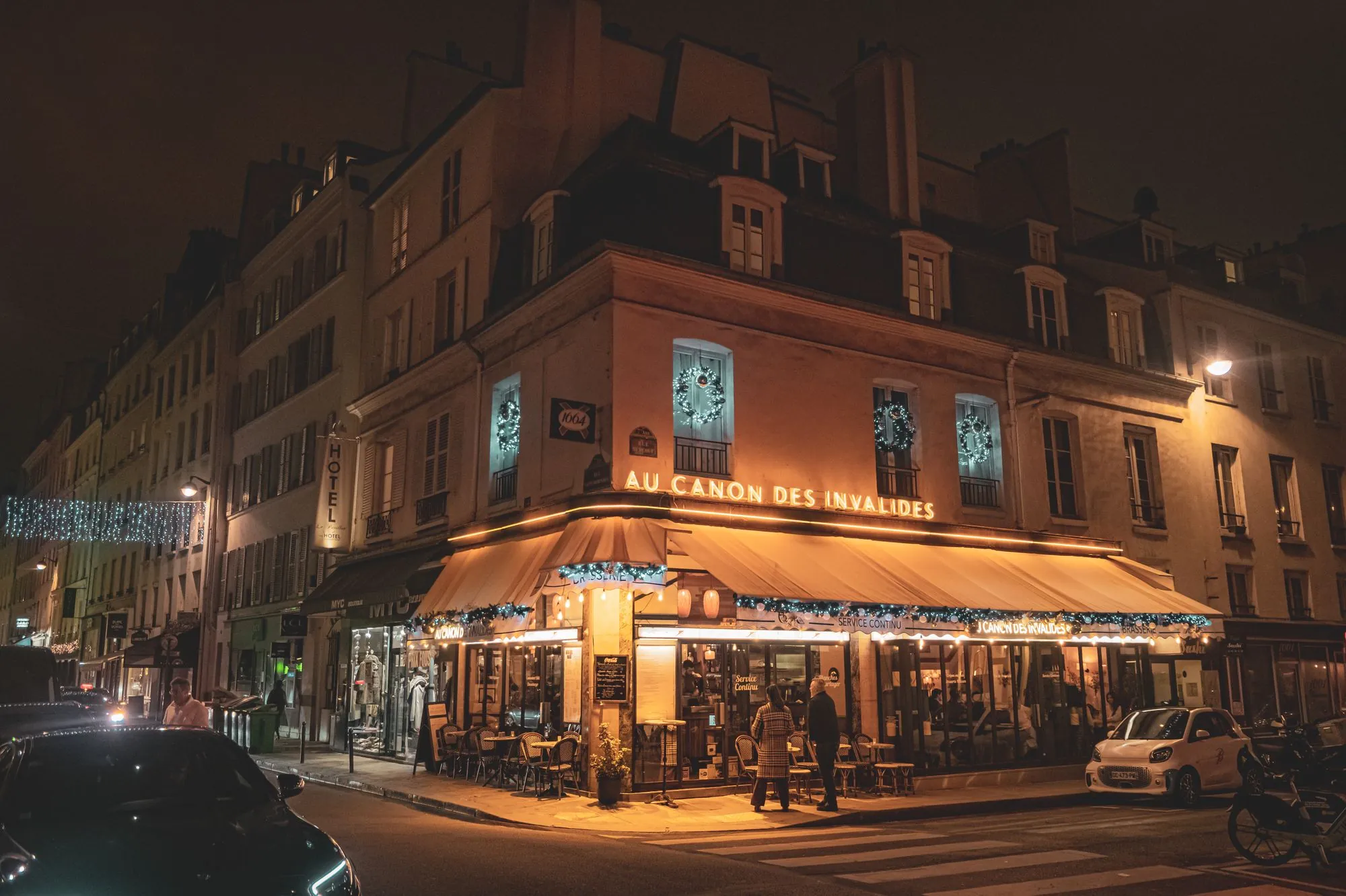 A Parisian café glowing on a street corner at night